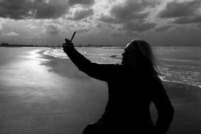 Woman taking selfie through mobile phone at beach