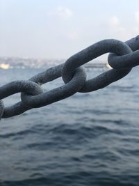 Close-up of chain against sea 