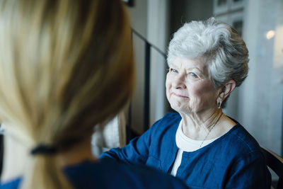 Happy senior woman looking at home caregiver