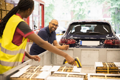 Smiling male customer leaning on trailer while talking to sales staff scanning at checkout counter