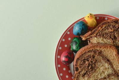 Directly above view of easter eggs and cake served in plate on white background
