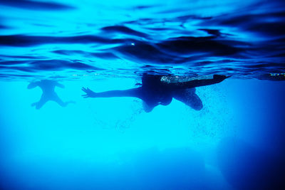 Silhouette of people swimming in sea