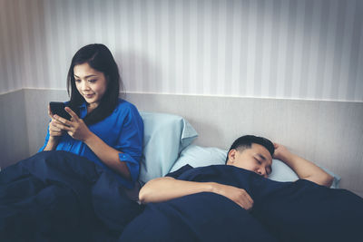 Full length of man using mobile phone on bed