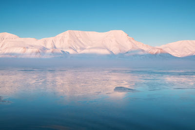 Scenic view of snowcapped mountains against blue sky