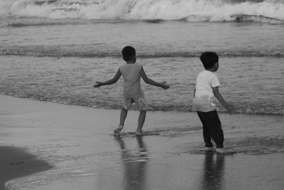 Rear view of boys standing on beach