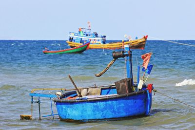 Fishing boats moored on sea against clear sky