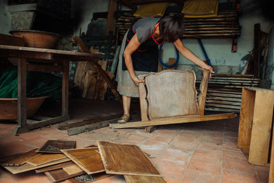 Female artisan working reusing old wooden furniture for artistic use