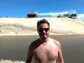 Portrait of shirtless man wearing sunglasses at beach