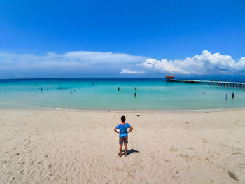 Rear view of man standing at beach against sky