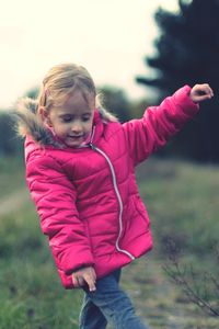 Cute girl with arms raised on field