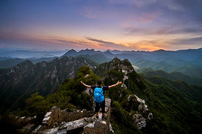 Man standing on mountain against sky during sunset