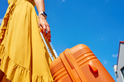 Low section of woman with umbrella against blue sky