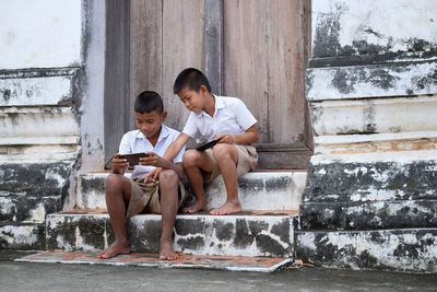 Male friends using phones while sitting on steps