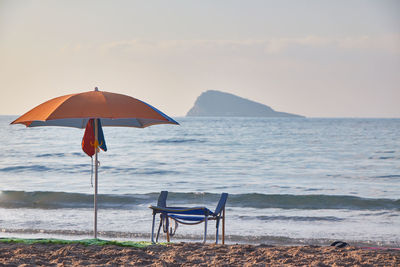 Deck chairs on beach against sky