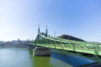 Liberty bridge over danube river against clear sky in city