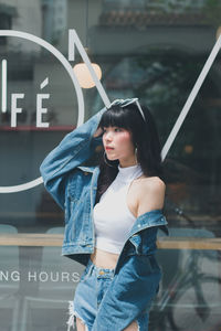 Side view of thoughtful young woman standing outside cafe 