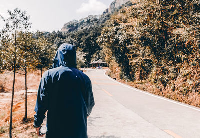 Rear view of man walking on road