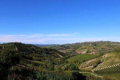 Scenic view of landscape against blue sky in langhe, piedmont.  towns, vineyard and nature.