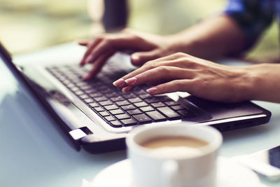 Midsection of person using laptop on table