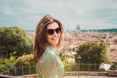 Profile portrait of young smiling woman in sunglasses with a panoramic view of rome, italy
