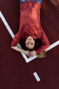 High angle portrait of young woman lying down on running track