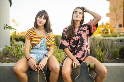 Two beautiful young women sitting resting and laughing with their long boards