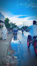 Rear view of people on road against blue sky