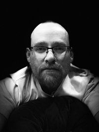 Portrait of man wearing eyeglasses against black background