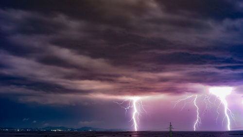 Panoramic view of lightning over sea against storm clouds