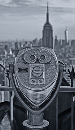 Close-up of coin-operated binoculars against cityscape