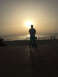 Silhouette man on beach against clear sky during sunset