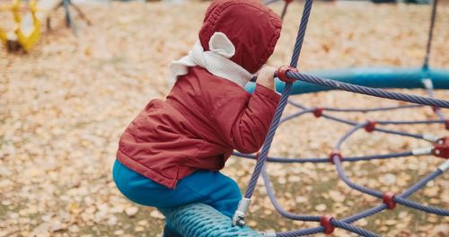 Low angle view of girl playing on rope in playground