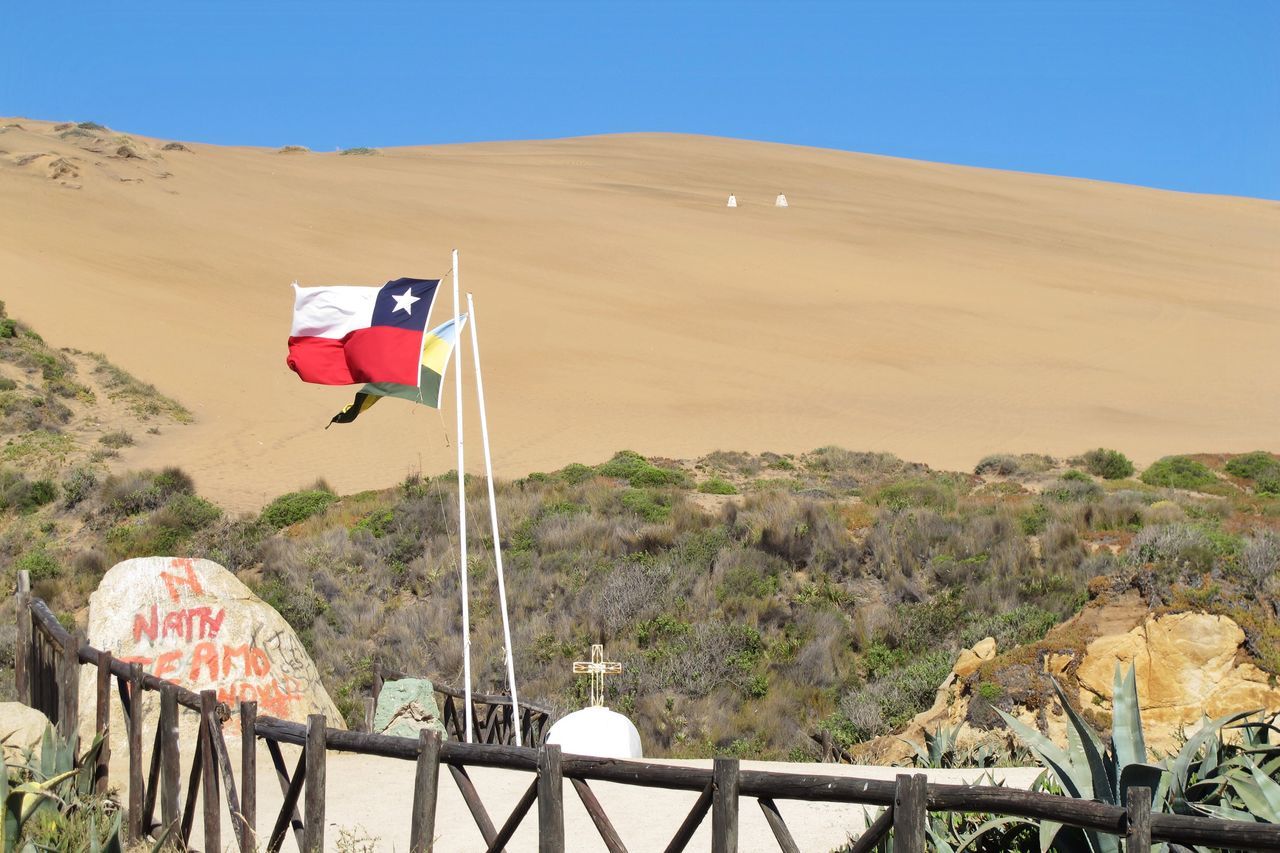 clear sky, mountain, transportation, blue, red, built structure, mountain range, flag, copy space, railing, landscape, sunlight, day, architecture, mode of transport, outdoors, no people, nature, sky, travel