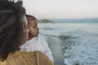 Side view of mother and daughter embracing in the ocean negative space