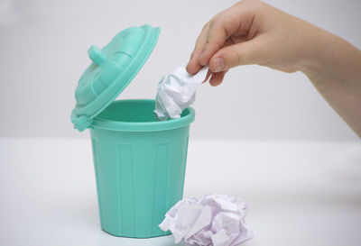 Close-up of hand holding bottle against white background