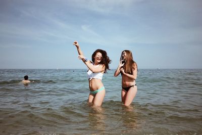 Female friends standing in sea