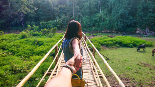 Rear view of woman holding hand on footbridge