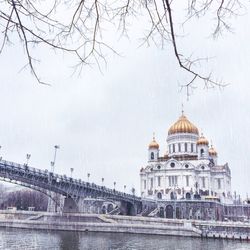 Bridge over river by cathedral against sky