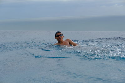 Boy swimming on the swimming pool and view the sea at morning