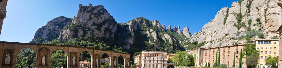 Low angle view of buildings and mountain against blue sky