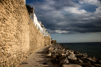 Stone wall by sea against sky