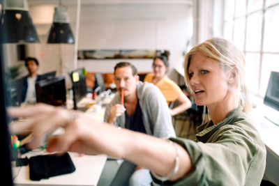 Female entrepreneur explaining business strategy to coworkers in office meeting