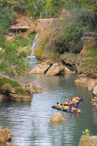 View of people sitting on rock by river