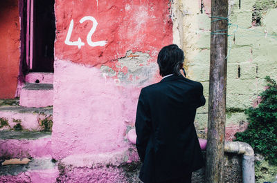 Rear view of man standing against wall in city