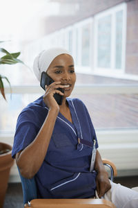 Young female doctor talking on phone at work