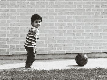 Side view portrait of boy gesturing while standing by soccer ball