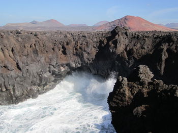 Scenic view of rocky mountains by sea against sky