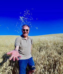 Full length of smiling man standing on field against sky