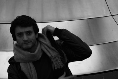 Portrait of young man listening music against metal wall