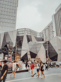 People walking on street against buildings in city